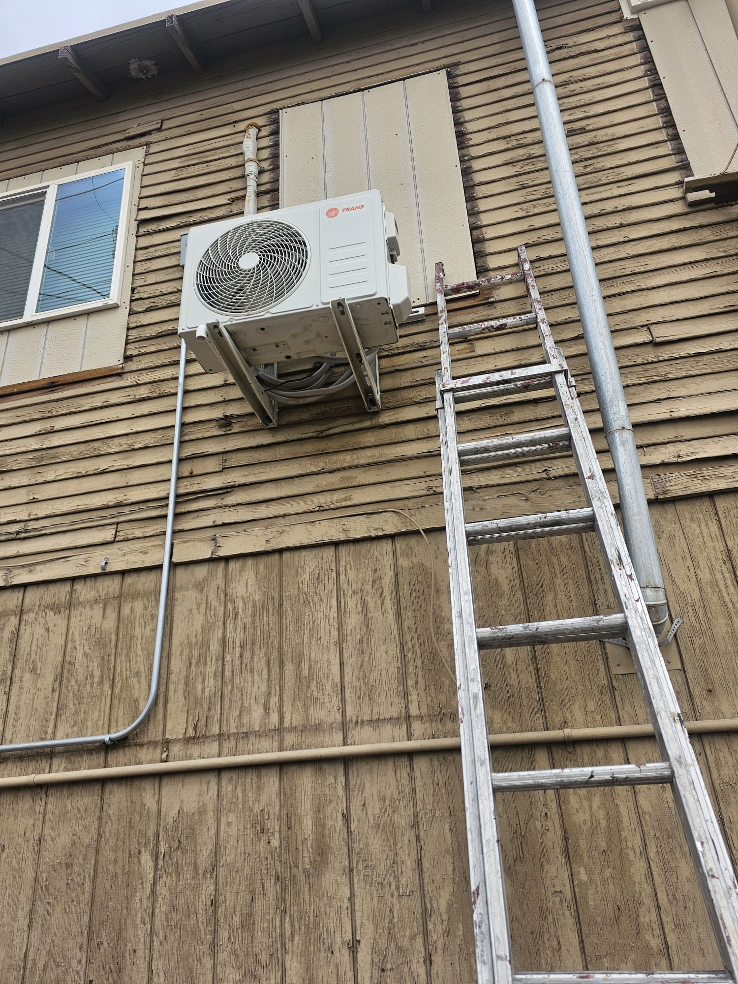 Unidad condensadora instalada en un muro exterior con escalera de servicio